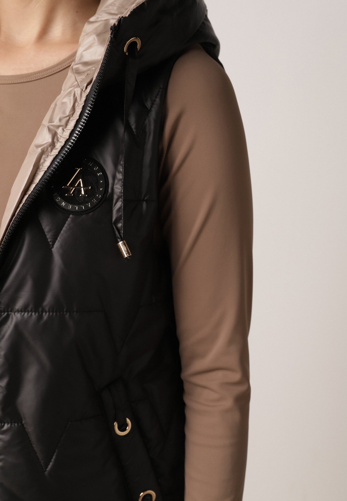 Czarna Pikowana Kamizelka o Długim Kroju z Nieodpinanym Kapturem i Aplikacją Koretes