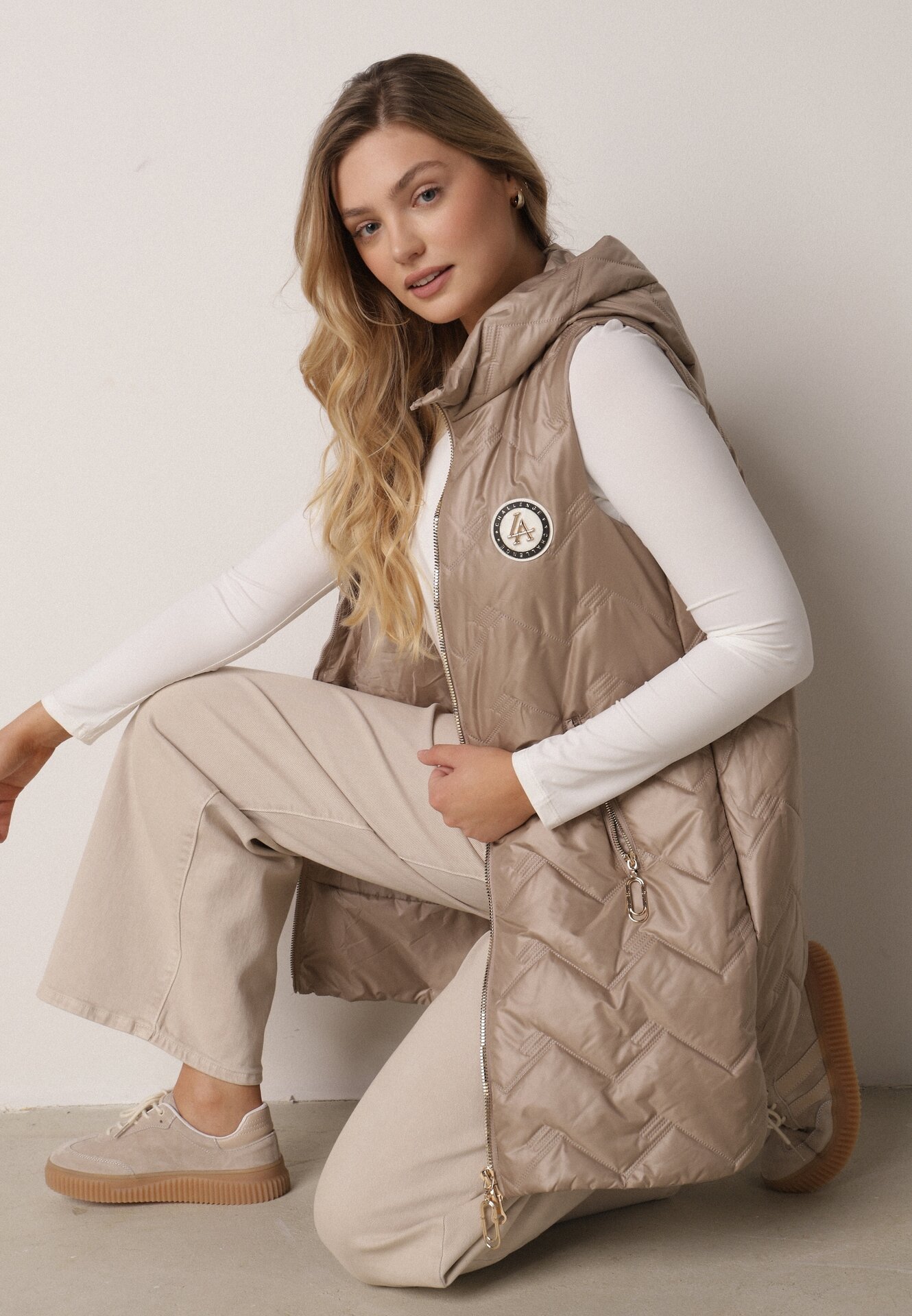 Brązowa Przejściowa Kamizelka Pikowana o Długim Kroju z Kapturem i Naszywką Harmaste