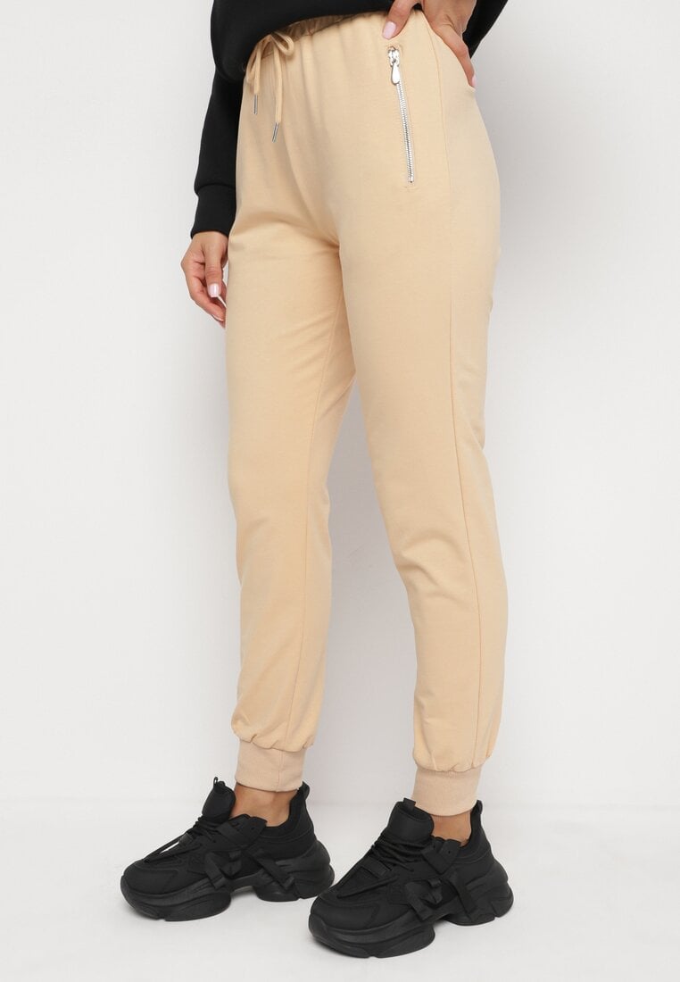 Pantaloni de trening bej de bumbac cu talie înaltă, finisați cu fermoare și panglică Dedela